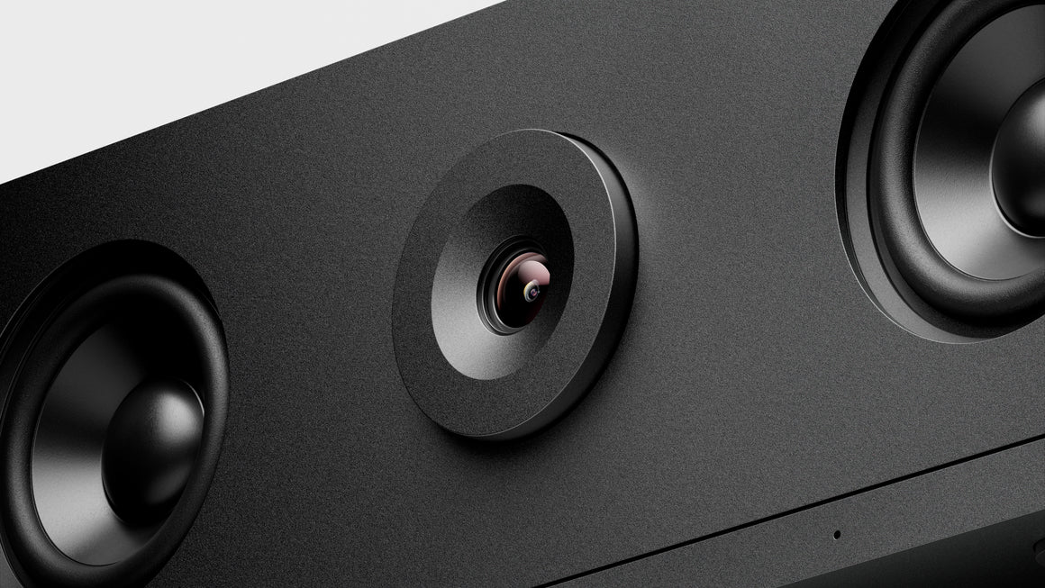Close-up of a black electronic device with a camera lens and speakers.