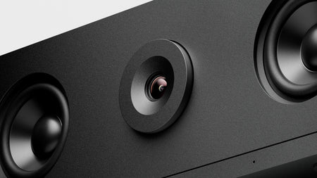 Close-up of a black electronic device with a camera lens and speakers.